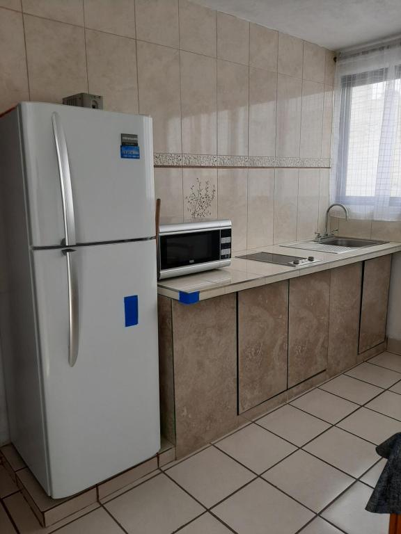 een keuken met een witte koelkast en een wastafel bij Casa la Estación in Mexico-Stad