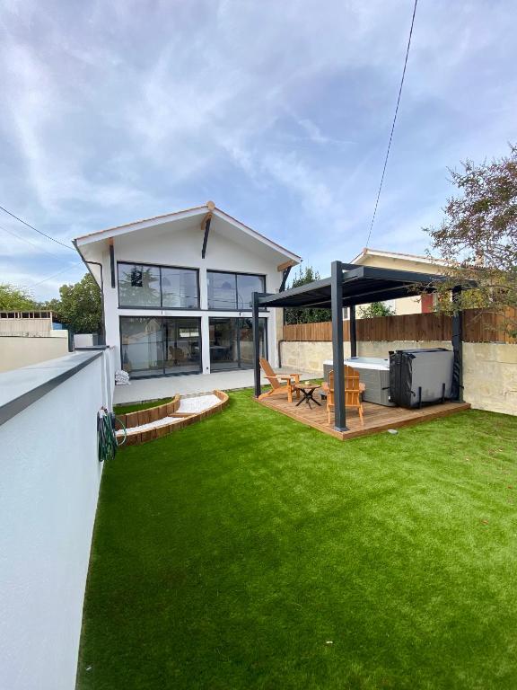 une maison avec une cour avec de l'herbe verte dans l'établissement Magnifique grange avec spa / love room, à Saint-André-de-Cubzac