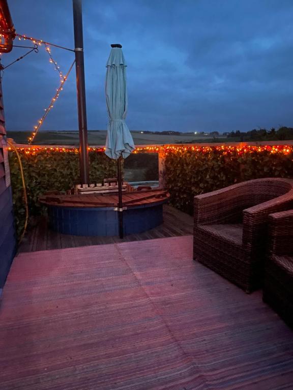 un parasol et des chaises sur une terrasse éclairée dans l'établissement Croft B&B Accommodation With Hot Tub, à Gamrie