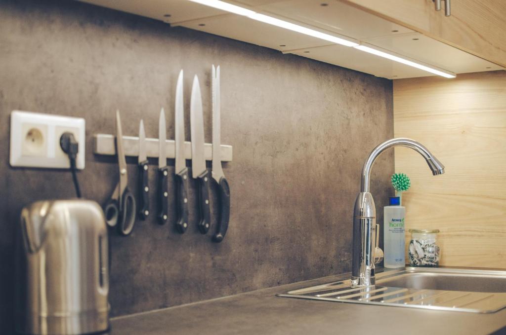 a kitchen counter with a sink and knives on a wall at Oltec Apartment Brno in Brno