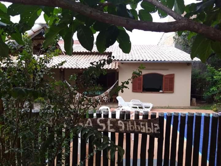 a house with a sign in front of a fence at Casa das orquídeas in Santana do Riacho