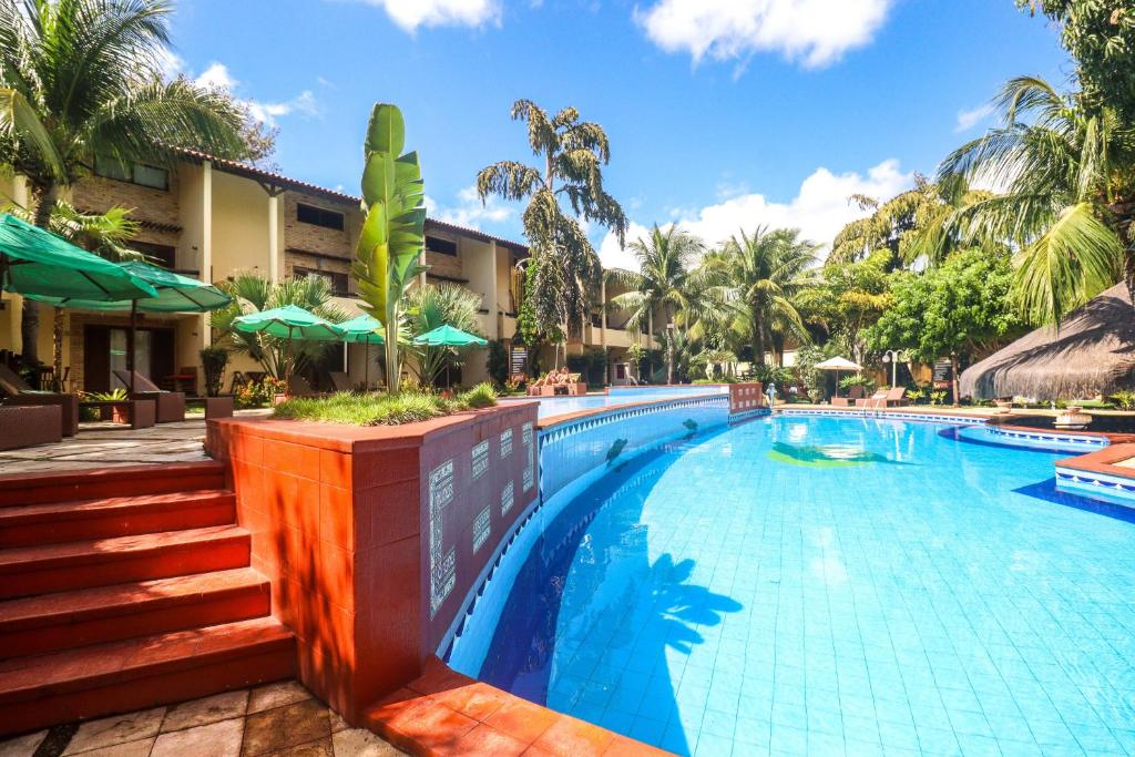 a swimming pool at a resort with palm trees at Solar Pipa - Solar da Gameleira Flats in Pipa