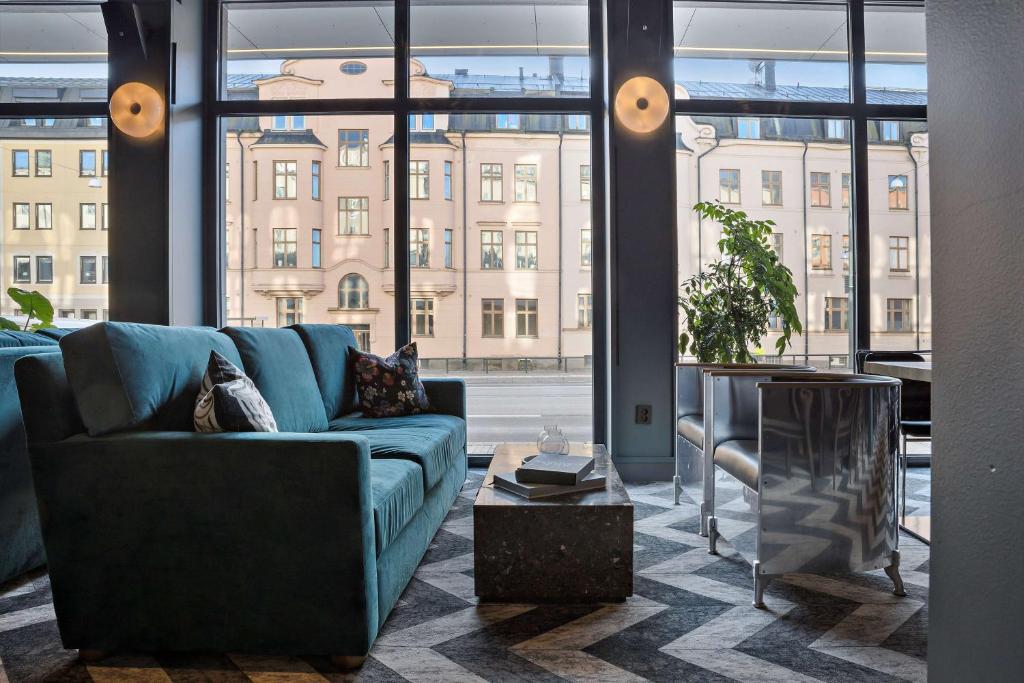 a living room with a blue couch and a large window at Best Western and Hotel Linkoping in Linköping