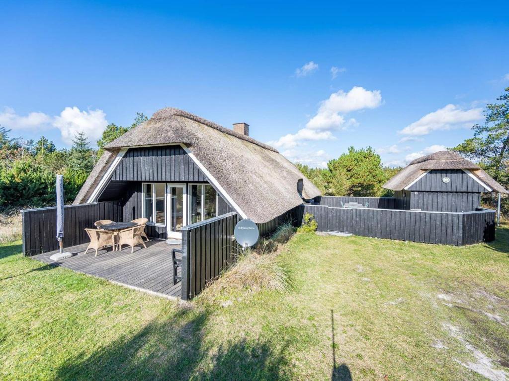 a thatch roofed house with a deck and a table at Holiday home Nørre Nebel XLIX in Nørre Nebel