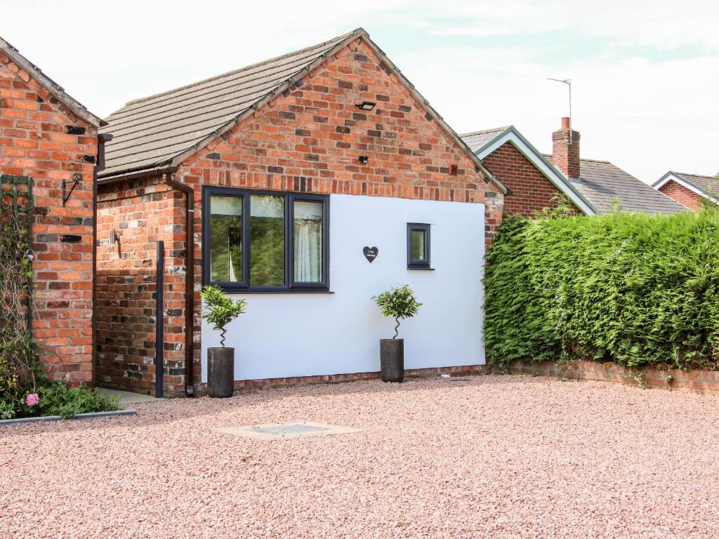 una casa de ladrillo con un garaje blanco con dos macetas en Oakleigh, en Llanymynech