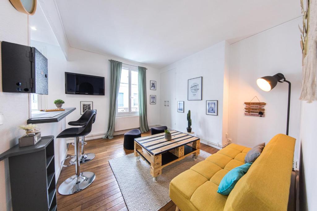 ein Wohnzimmer mit einem gelben Sofa und einem Tisch in der Unterkunft Appartement T2 au calme Cosy - Quartier Prébendes in Tours