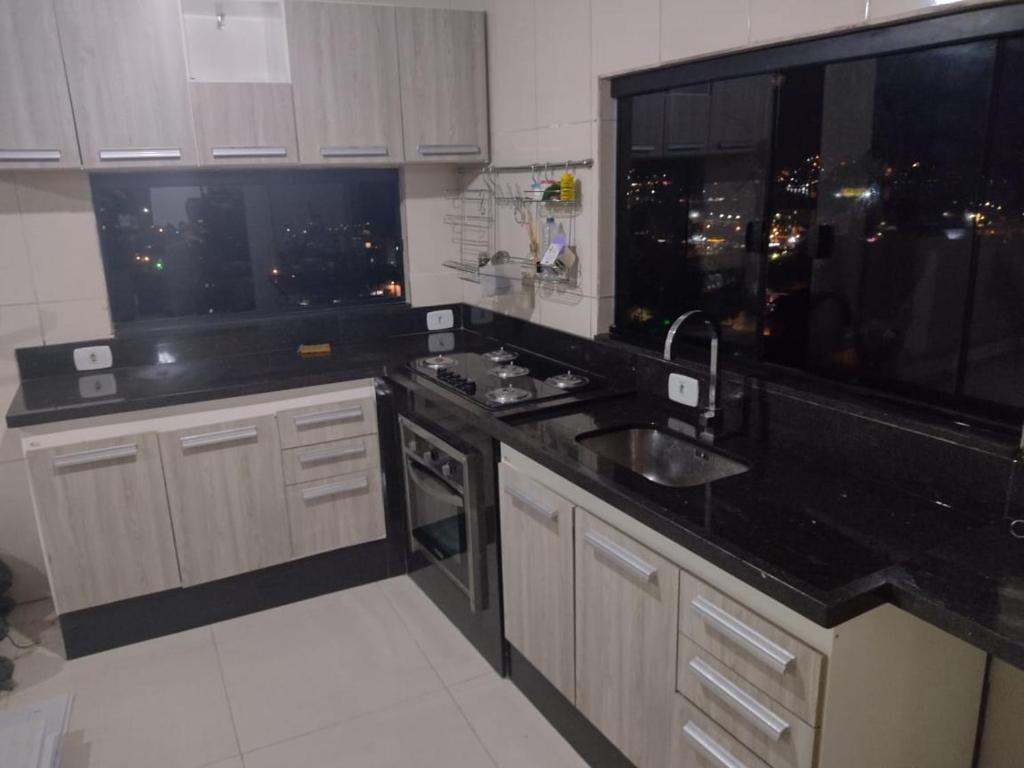 a kitchen with a black counter top and a sink at Hospedagem da Val in Angra dos Reis
