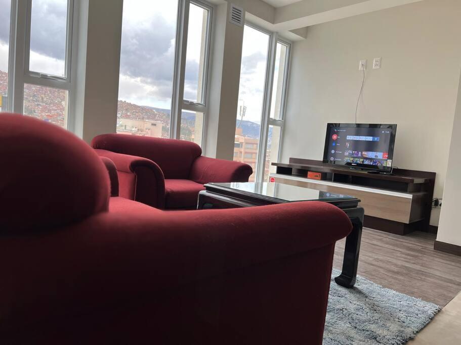 a living room with two red chairs and a tv at Apartamento Nuevo con Hermosa Vista, Ubicación Perfecta in La Paz