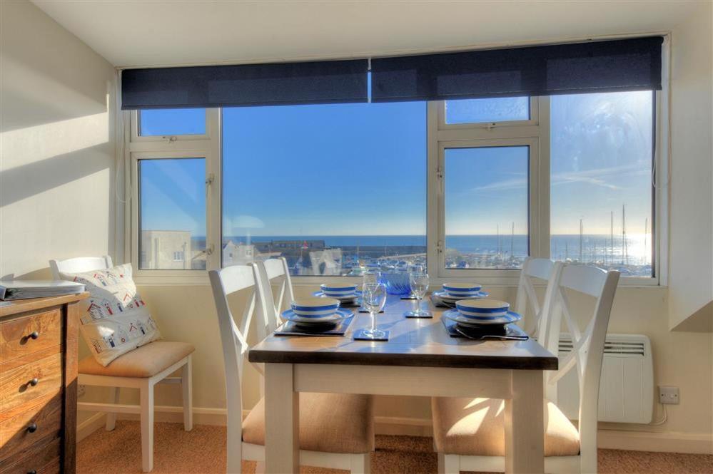 a dining room with a table with chairs and a large window at Halyards, La Casa in Lyme Regis