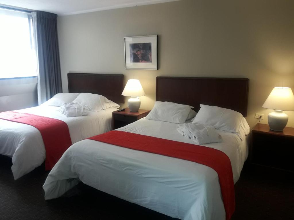 2 camas en una habitación de hotel con 2 lámparas en Suite cómoda y elegante., en Quito