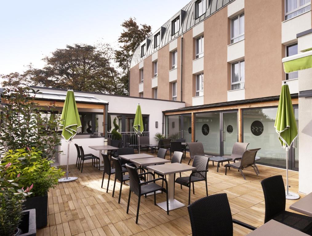 un patio avec des tables et des chaises et un bâtiment dans l'établissement ibis Styles Beaune Centre, à Beaune