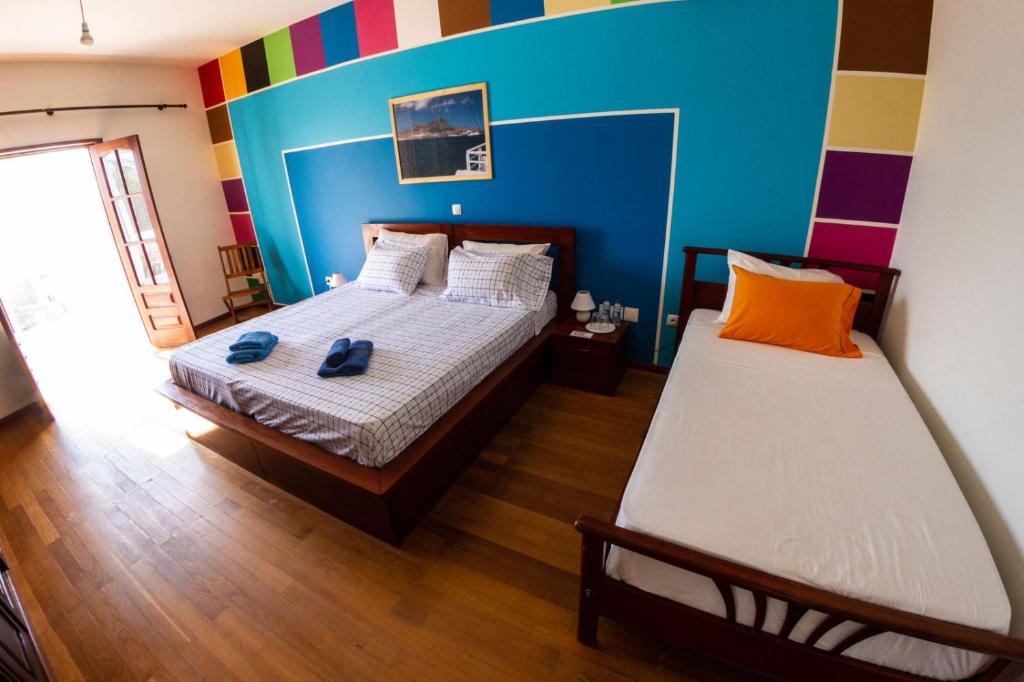 a bedroom with two beds and a colorful wall at Guest House Montanha in Mindelo
