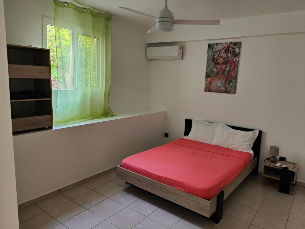 - une chambre avec un lit rouge et une fenêtre dans l'établissement Rayon de Soleil T2 Bas de villa, à Sainte-Anne