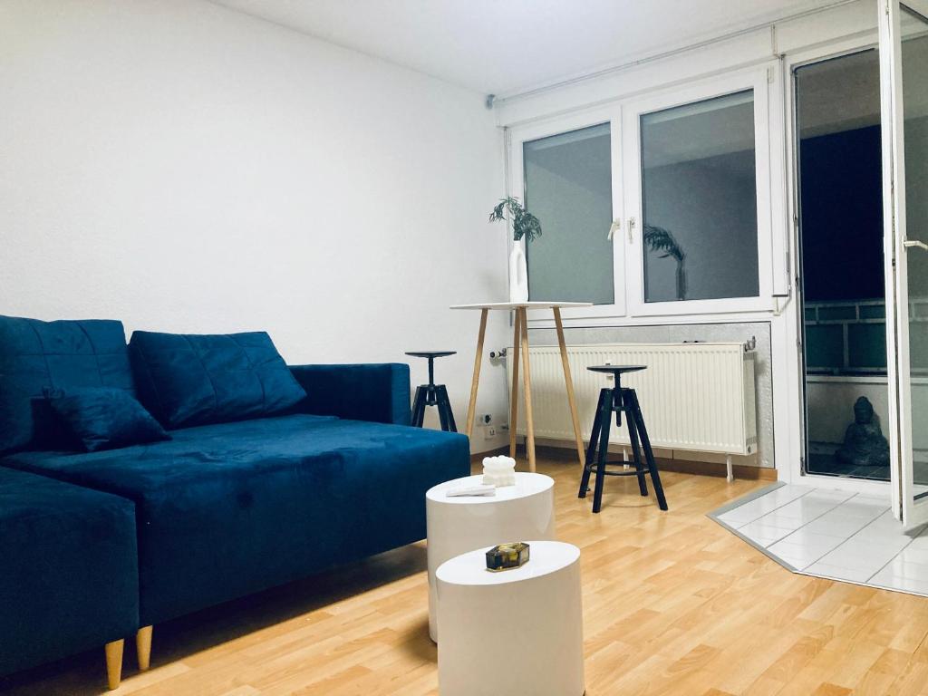 a living room with a blue couch and two white tables at Taunus top floor Balkon Altstadt Messe Frankfurt 10 min in Oberursel