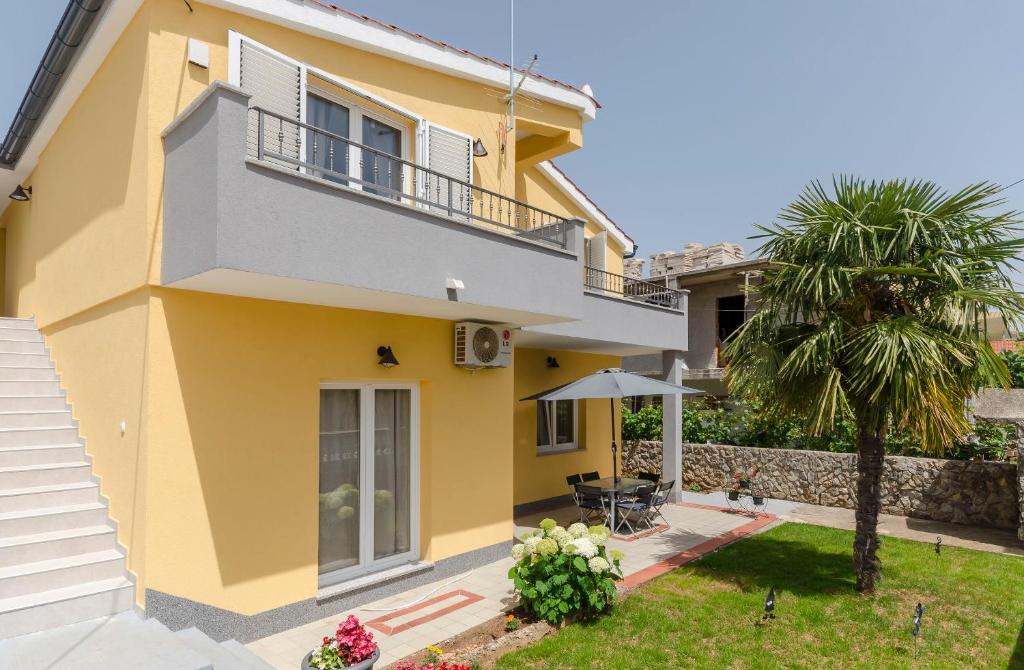 a yellow house with a balcony and a palm tree at Apartment Tarle in Vodice