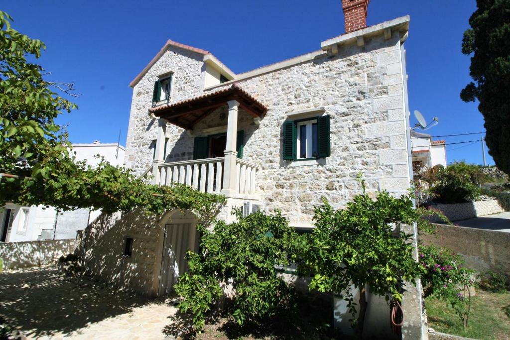 a white stone house with green shutters at Apartment and Room Lada in Sumartin
