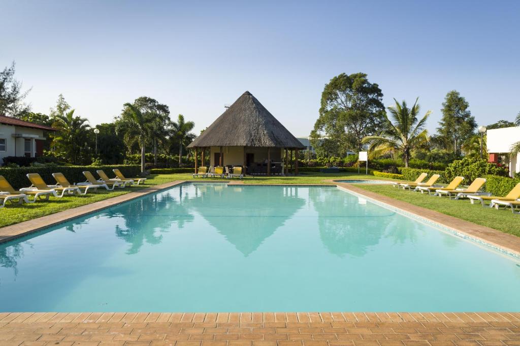 a large swimming pool with chairs and a gazebo at Montebelo Indy Maputo Congress Hotel in Maputo