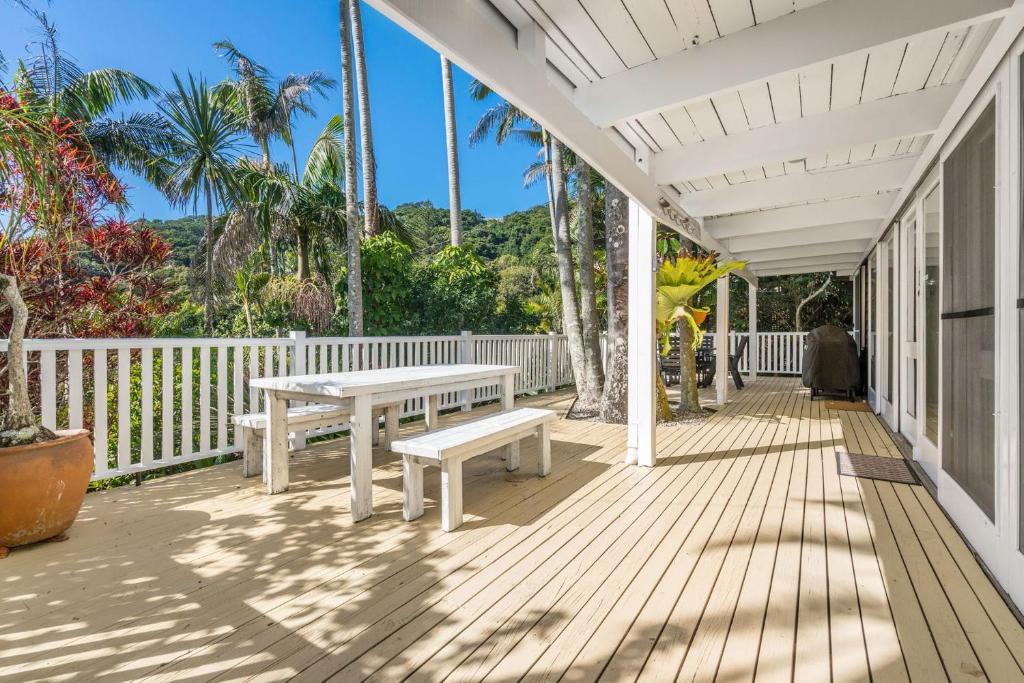 un porche blanco con banco y mesa en Lower Decks, en Byron Bay