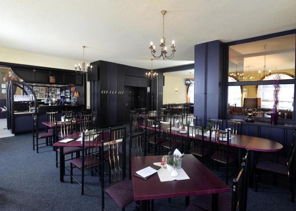 a restaurant with tables and chairs and a bar at Hotel U Jezírka in Liberec