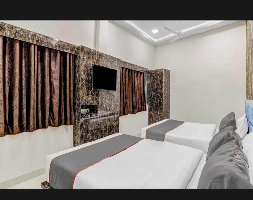 Hotel Bhavya Residency في Jāmb: غرفة نوم بسريرين وتلفزيون بشاشة مسطحة