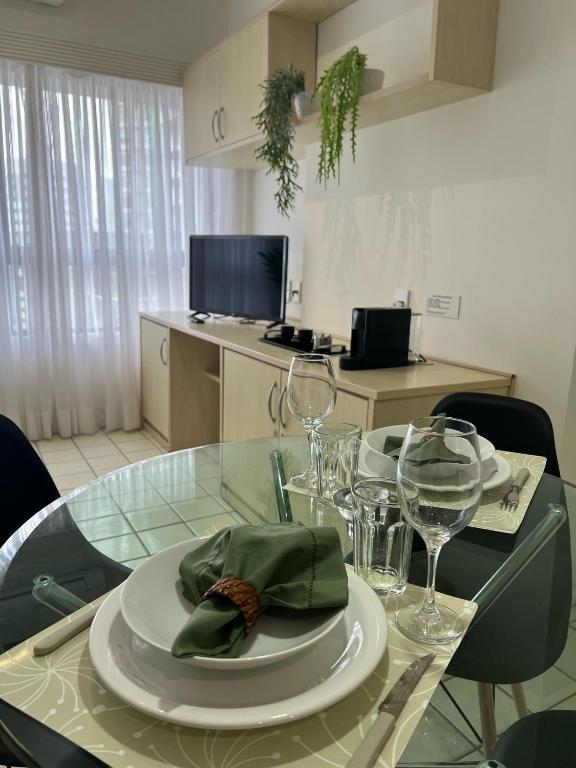 a glass table with a plate with a napkin and wine glasses at Flat - Navegantes Residence Hotel in Recife