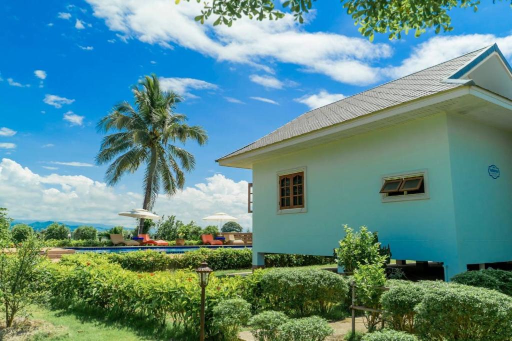 a white house with a palm tree in the background at Baan innto resort in Fang