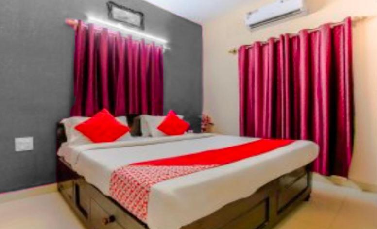 1 dormitorio con 1 cama grande y cortinas rojas en JK BNB Stay, en Vagator