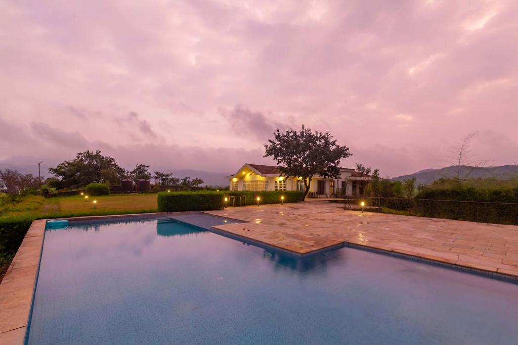 una piscina con una casa en el fondo en StayVista's Shivom Villa 12 - A Serene Escape with Views of the Valley and Lake, en Lonavala