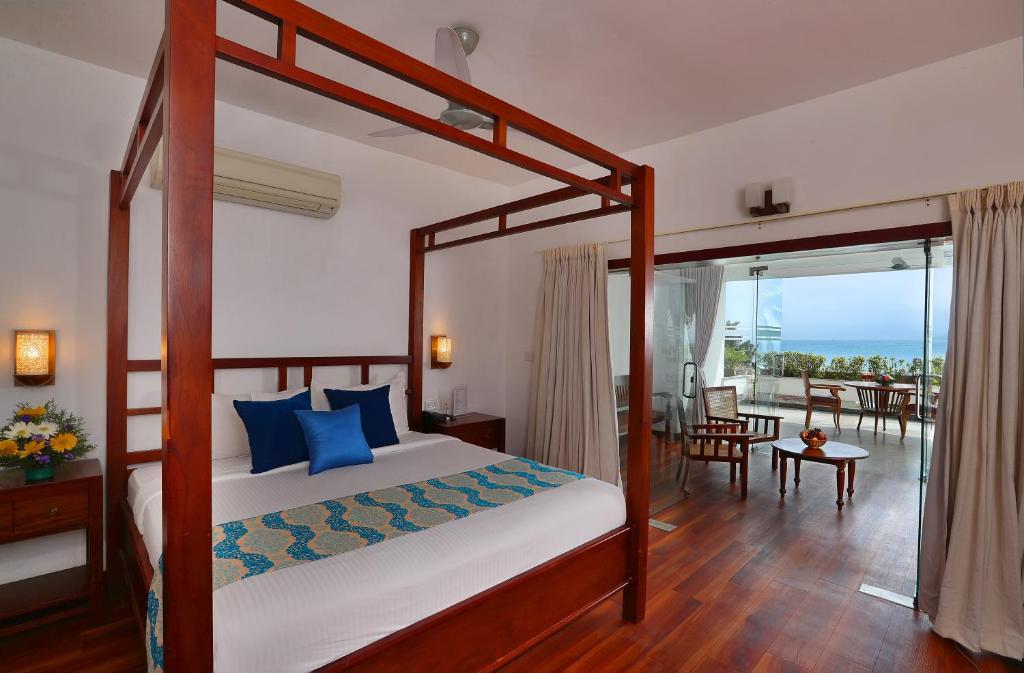 Schlafzimmer mit Himmelbett und Balkon in der Unterkunft Getaway Beach Resort Kovalam in Kovalam