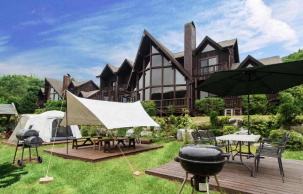 a house with a grill and tables and umbrellas at Chalet Resort in Pyeongchang 