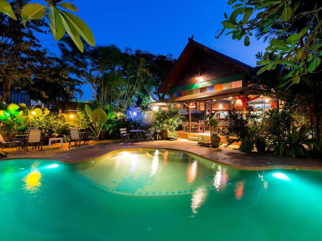 a swimming pool in front of a house at night at Shanti Lodge Phuket in Chalong 
