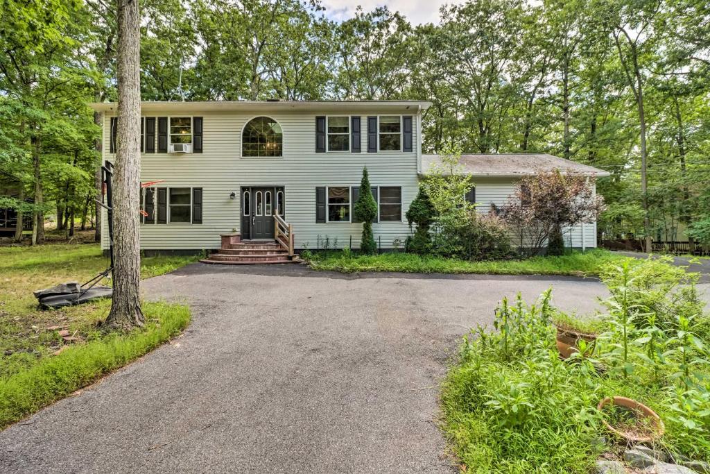 una casa blanca con un árbol y una entrada en Pocono Gem with Deck and Fire Pit, 9 Mi to Skiing!, en Bushkill