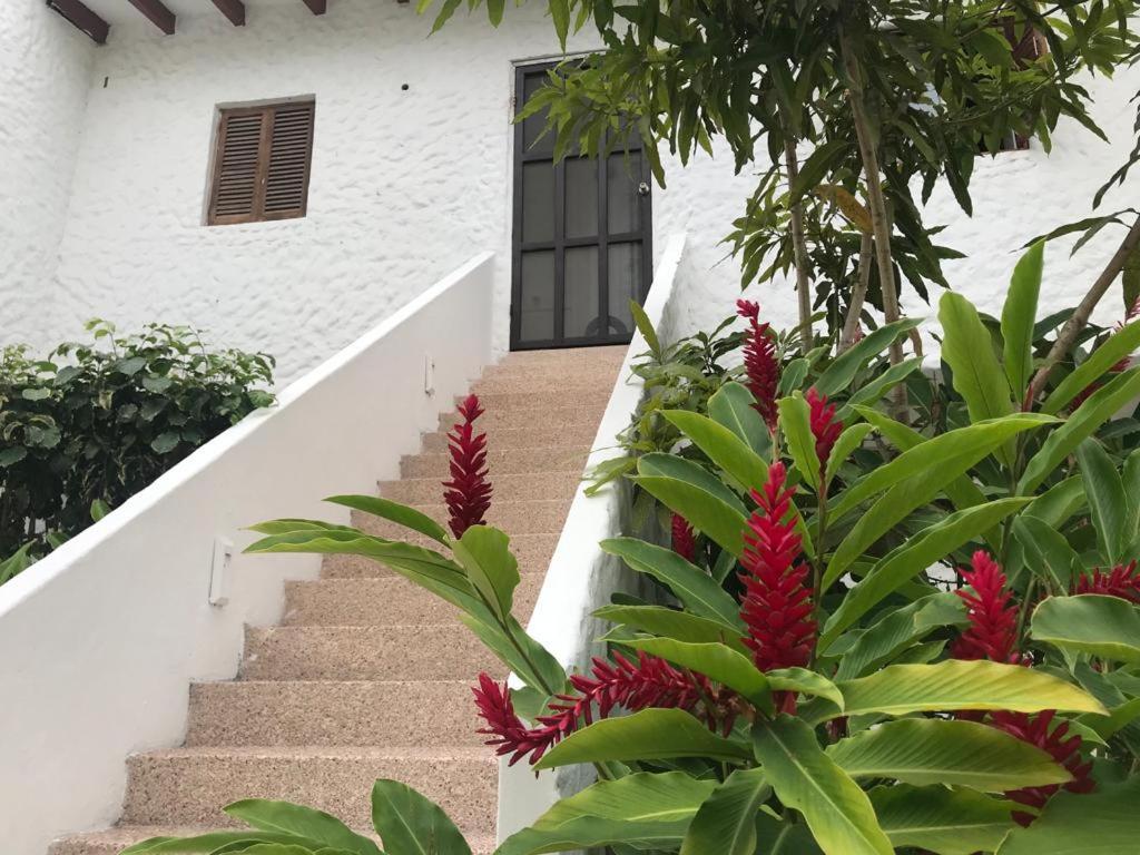 un conjunto de escaleras que conducen a una casa con flores rojas en Vacaciones Playa Club Casa Blanca Same Esmeraldas en Same