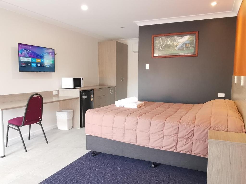 sypialnia z łóżkiem, biurkiem i krzesłem w obiekcie Homestead Motel w mieście Dubbo
