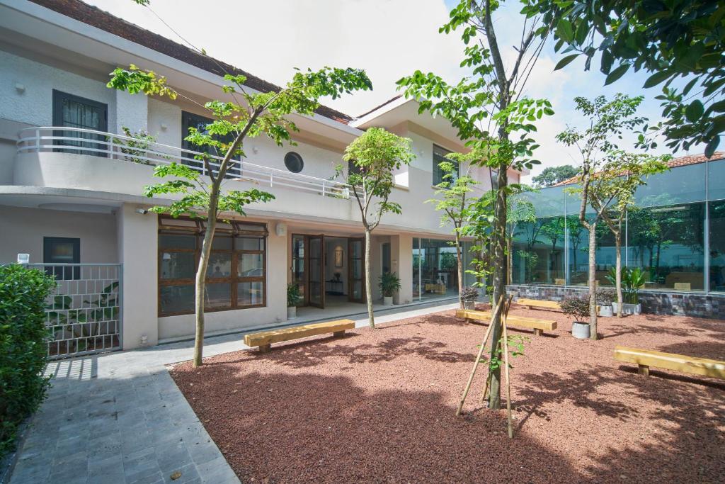 un edificio con bancos y árboles delante de él en M Village Tú Xương en Ho Chi Minh