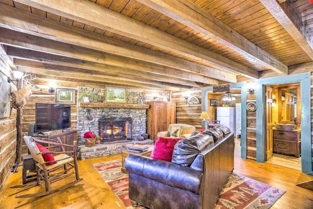 Lovely Pet-Friendly Flat Rock Cabin from 1905 في Rising Fawn: غرفة معيشة مع أريكة جلدية ومدفأة