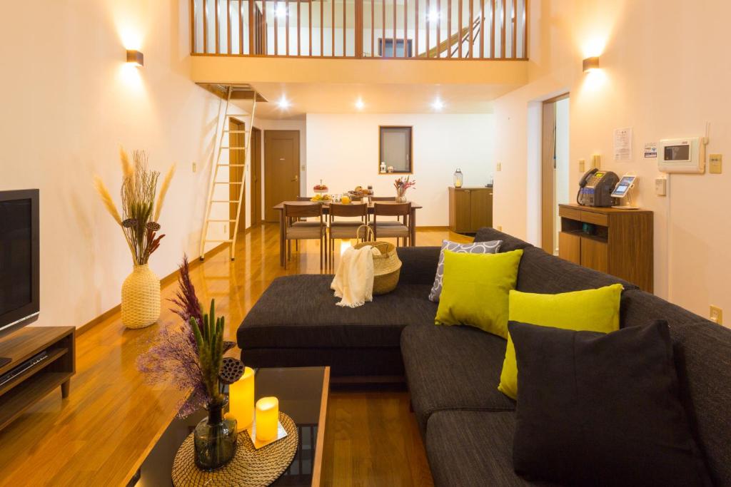 uma sala de estar com um sofá cinzento e almofadas amarelas em スイートヴィラパノーラ八ヶ岳 em Kunizakai
