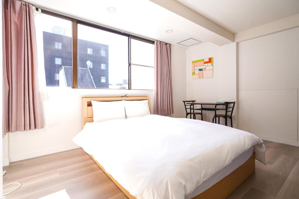 Un dormitorio con una cama blanca y una ventana. en Shirakabanoyado - Doutonbori 道頓堀, SELF CHECK IN ONLY, en Osaka