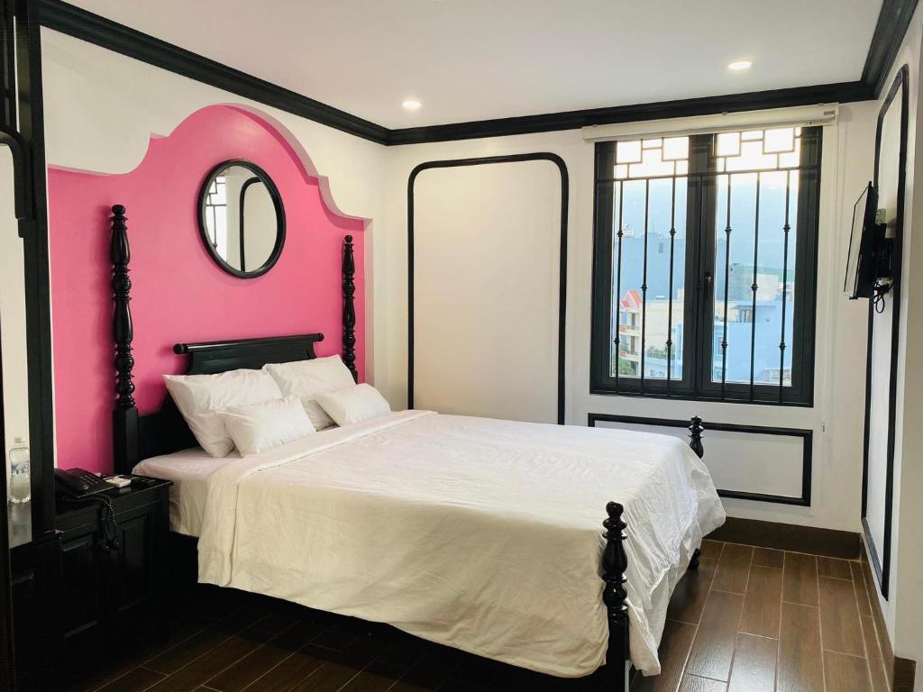a bedroom with a large bed with a pink wall at The Fancy House in Quy Nhon