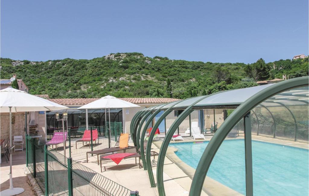 une piscine avec chaises et parasols à côté d'un bâtiment dans l'établissement Lovely Home In Rochefort Du Gard, à Rochefort-du-Gard