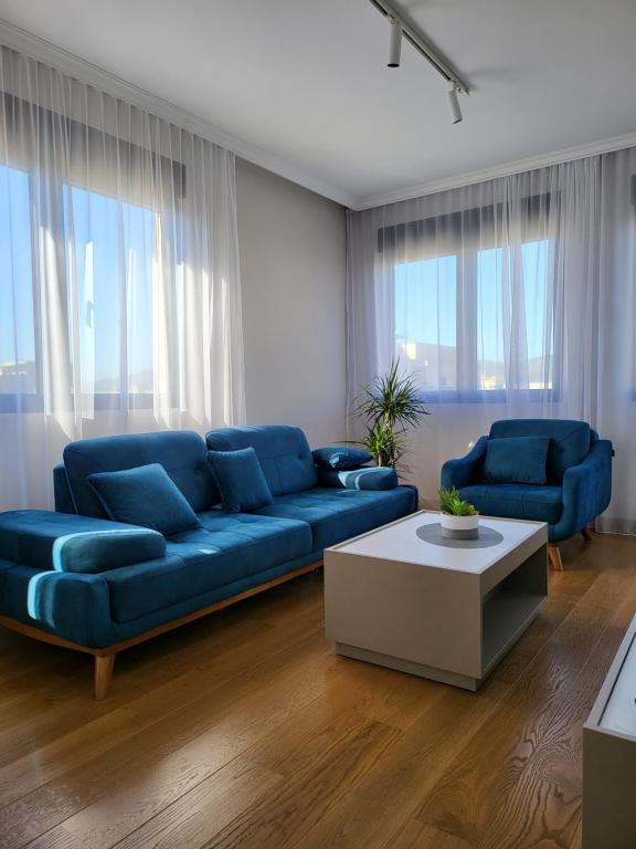 uma sala de estar com um sofá azul e uma mesa em Green Apartments Podgorica With Garage em Podgorica