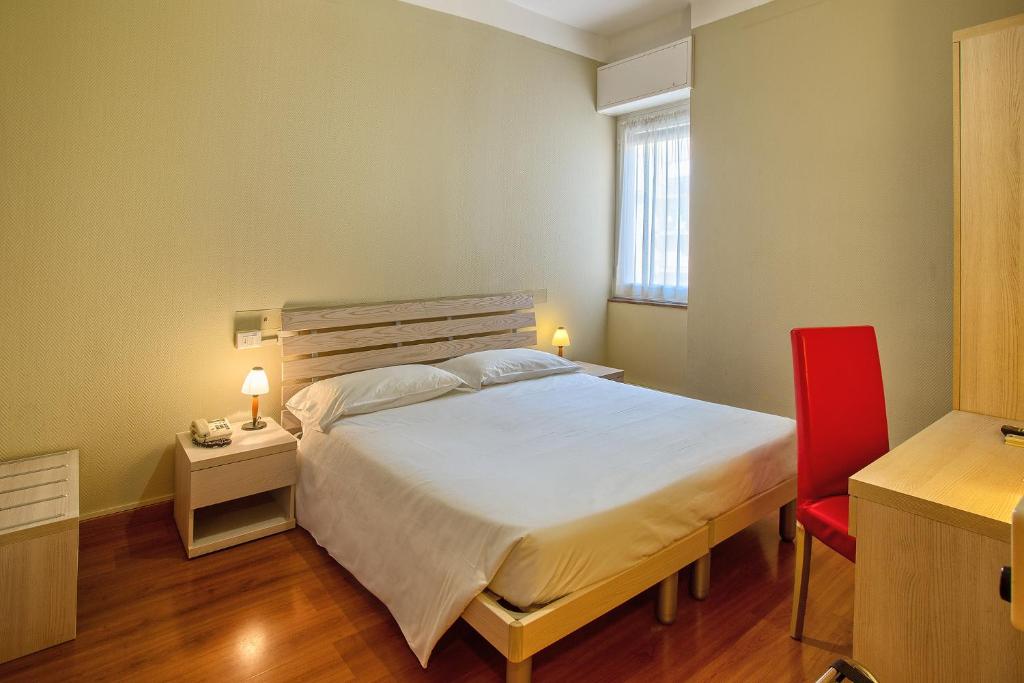 a bedroom with a large bed and a red chair at Hotel Calypso in Ventimiglia
