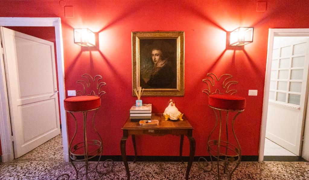 Czerwony pokój z dwoma stołkami, stołem i obrazem w obiekcie The Apartment Genova w Genui