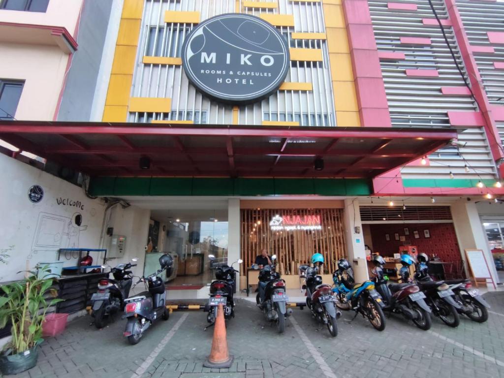 un grupo de motocicletas estacionadas frente a un edificio en Miko Rooms & Capsules hotel en Bungurasih