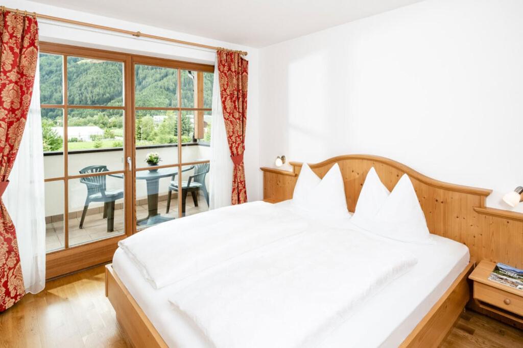 um quarto com uma cama branca e uma varanda em Fini's Apartments em Vipiteno