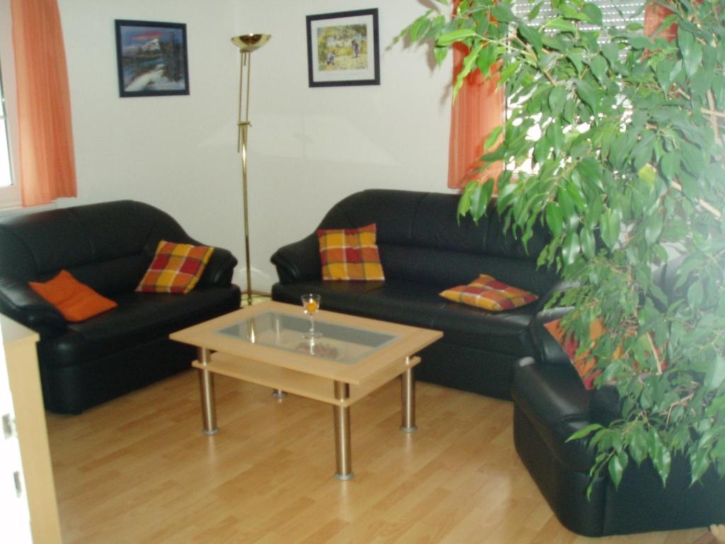 Sala de estar con 2 sofás negros y mesa de centro en FeWo Neubert en Bad Kissingen