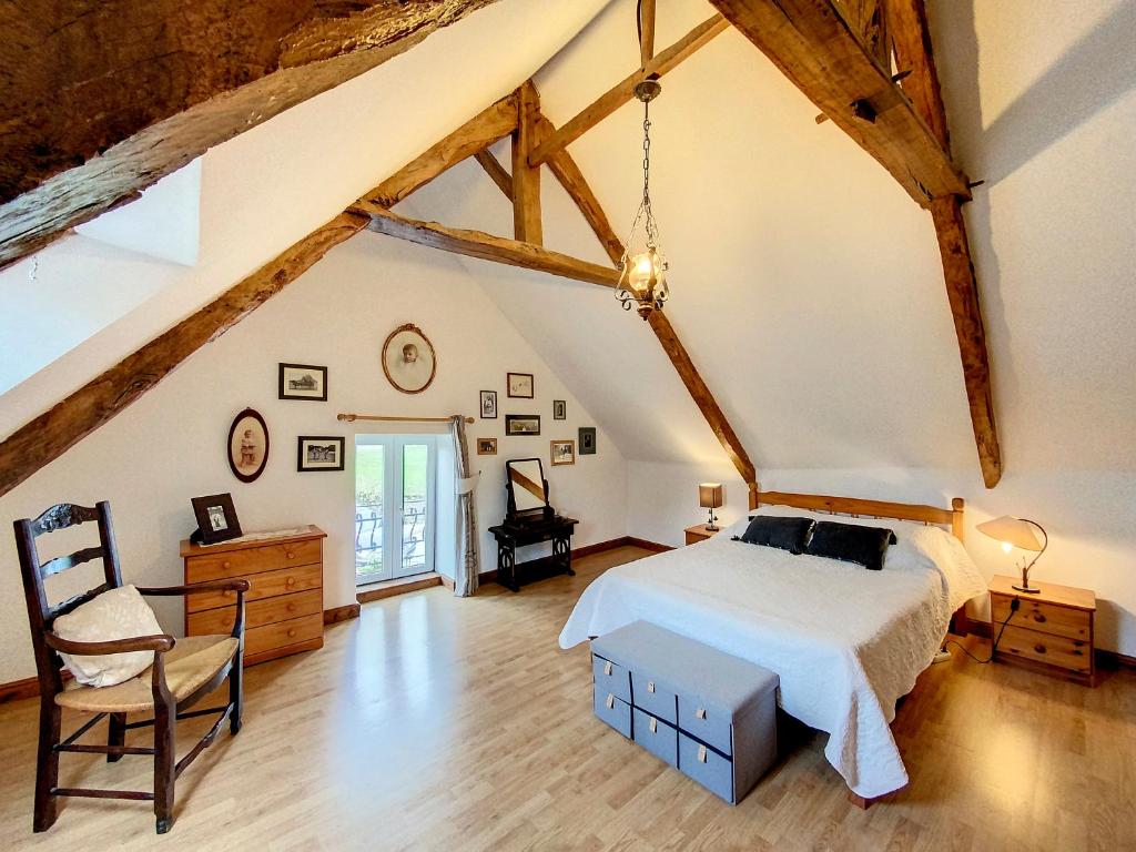 um quarto com uma cama e uma cadeira num sótão em Gîtes Les Villes Briend em Pluduno