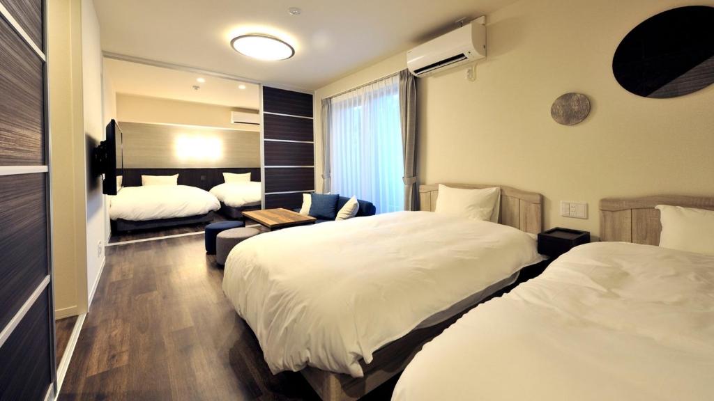 a hotel room with two beds and a couch at RakutenSTAY x Shamaison Osaka Dekijima - 303 in Osaka