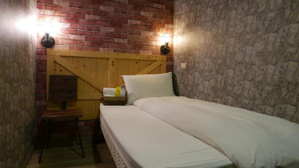a bed in a room with a brick wall at NYS Loft Hotel in Taipei