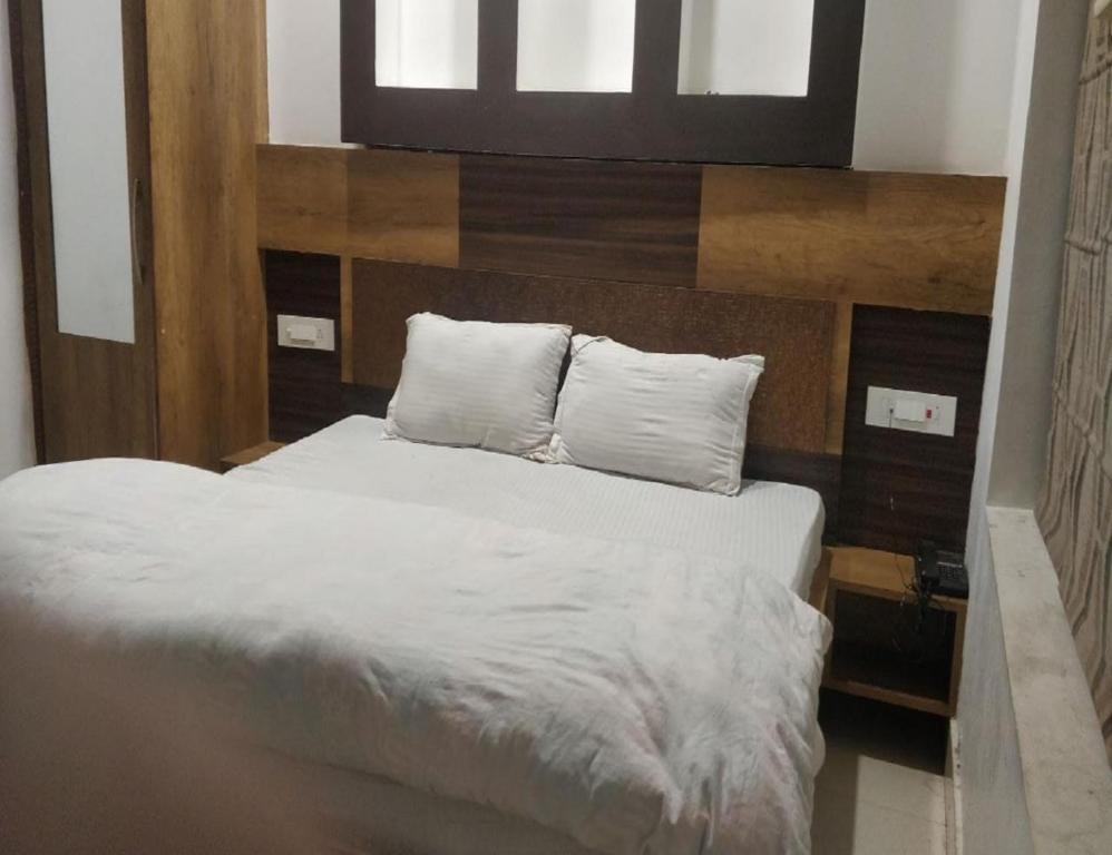 1 dormitorio con 1 cama con sábanas y almohadas blancas en Hotel Bansal Residency, Sirsa, en Sirsa